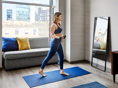 a woman standing on a blue yoga mat in a living room at Gansevoort Meatpacking in New York