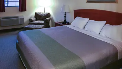 a hotel room with a large bed and a chair at Motel 6-Bloomsburg, PA in Bloomsburg