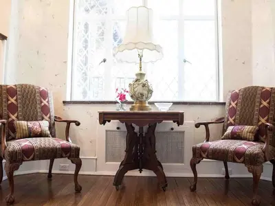 a table with a lamp and two chairs in a room at The Manor on Front in Harrisburg