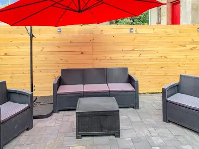 a patio with two couches and a red umbrella at Philly Coed Dorm!! 15 Min Train to Center City!! in Philadelphia