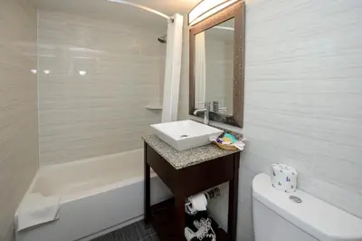 a white bathroom with a sink and a bath tub at Americas Best Value Inn at Central Valley-Woodbury in Central Valley