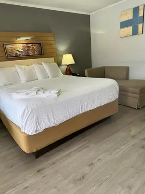 a bedroom with a large bed and a chair at Americas Best Value Inn at Central Valley-Woodbury in Central Valley