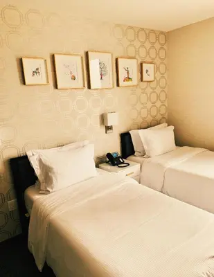 a hotel room with two beds and a phone on the wall at Hotel Mimosa in New York