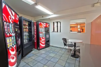 a restaurant with two soda machines and a table and chairs at Motel 6-East Brunswick, NJ in East Brunswick