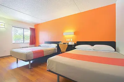 two beds in a room with an orange wall at Motel 6-East Brunswick, NJ in East Brunswick