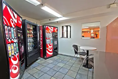 a restaurant with two soda machines and a table and chairs at Motel 6-East Brunswick, NJ in East Brunswick