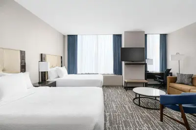 a hotel room with two beds and a couch at Fairfield Inn & Suites by Marriott New York Midtown Manhattan/Penn Station in New York