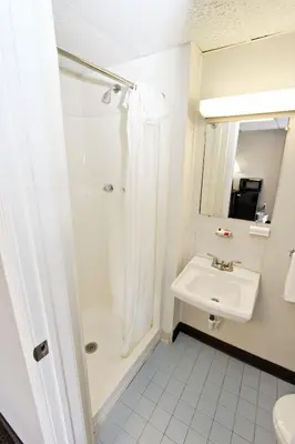 a white bathroom with a shower and a sink at Knights Inn Pine Grove in Pine Grove