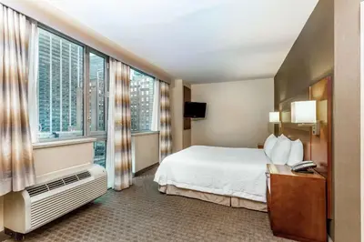 a hotel room with a bed and a large window at Hampton Inn Manhattan Grand Central in New York