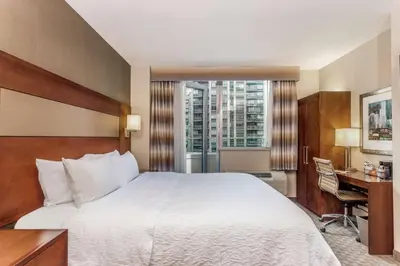 a hotel room with a bed and a desk and a window at Hampton Inn Manhattan Grand Central in New York