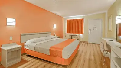 a bedroom with a large bed with an orange wall at Motel 6-Maple Shade Township, NJ - Philadelphia - Mt Laurel in Maple Shade