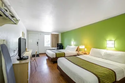 a hotel room with two beds and a flat screen tv at American Inn in Carlisle