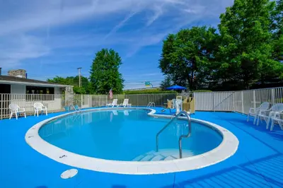 a large pool with blue water and white chairs at American Inn in Carlisle