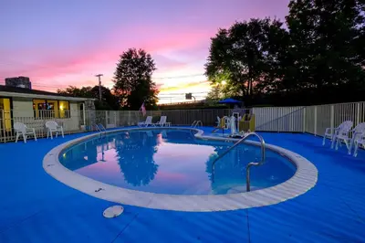 a large swimming pool with a sunset in the background at American Inn in Carlisle