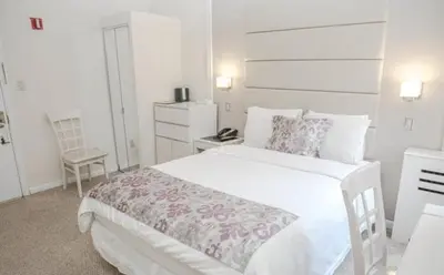 a white bedroom with a large bed and a chair at Da Vinci Hotel in New York