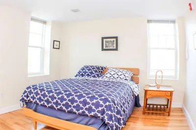 a bedroom with a bed and a table and windows at ⭐️Trendy Apartment⭐️Fishtown⭐️ in Philadelphia