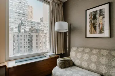 a hotel room with a couch and a large window at Club Quarters Hotel Grand Central, New York in New York