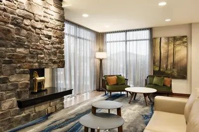 a living room with a fireplace and a stone wall at Fairfield Inn & Suites by Marriott Hershey Chocolate Avenue in Hershey