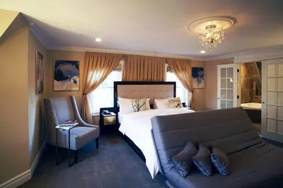 a bedroom with a bed and a couch and a chandelier at The Peacock Inn, an Ascend Collection Hotel in Princeton