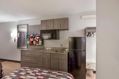 a kitchen with a stainless steel refrigerator and wooden cabinets at Red Roof Inn Philadelphia - Trevose in Trevose
