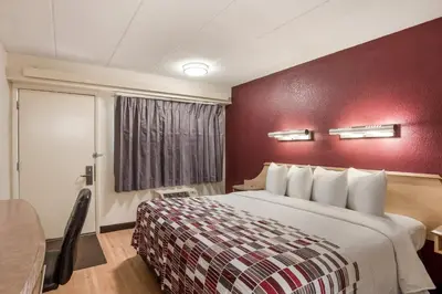 a hotel room with a bed and a red wall at Red Roof Inn Philadelphia - Trevose in Trevose