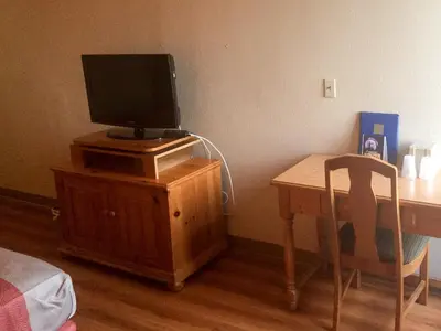 a bedroom with a desk with a tv on top of a wooden cabinet at Motel 6-Newark, DE in Newark