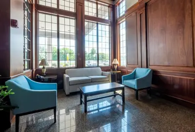 a living room with a couch and chairs and windows at Red Roof Inn & Suites Wilmington – New Castle in New Castle