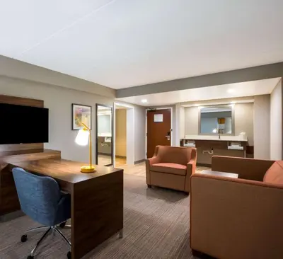 a living room with a couch and a desk with a television at Hampton Inn Philadelphia/Willow Grove in Willow Grove