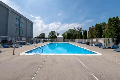 a large swimming pool with chairs and a building at Hampton Inn Swedesboro Philadelphia in Swedesboro