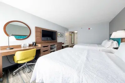 a hotel room with a bed and a desk and a mirror at Hampton Inn Swedesboro Philadelphia in Swedesboro