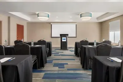 a conference room with tables and chairs and a screen at Holiday Inn Express & Suites Philadelphia - Mt Laurel by IHG in Mount Laurel