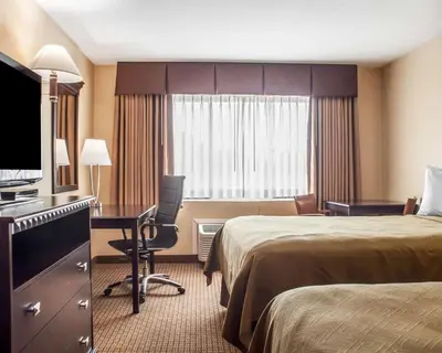 a hotel room with two beds and a desk at Econo Lodge Elmira-Corning in Elmira