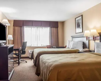 a hotel room with two beds and a desk at Econo Lodge Elmira-Corning in Elmira