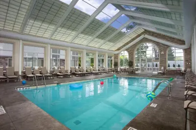 a large swimming pool with chairs and a glass ceiling at DoubleTree by Hilton Nanuet in Nanuet