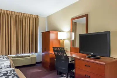 a hotel room with a desk with a television and a bed at Sleep Inn & Suites of Lancaster County in Mountville