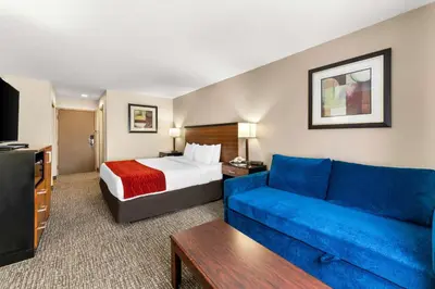 a hotel room with a bed and a blue couch at SureStay Plus by Best Western Reading North in Reading