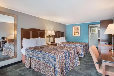 a hotel room with two beds and a mirror at Rodeway Inn Carlisle North in Carlisle