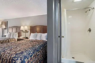 a hotel room with a bed and a shower at Rodeway Inn Carlisle North in Carlisle