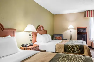 a hotel room with two beds and a chair at Comfort Inn Pine Grove I-81 Hershey Area in Pine Grove