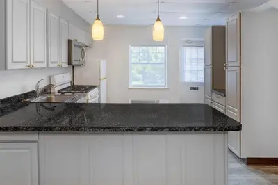 a kitchen with white cabinets and a black counter top at Baymont by Wyndham Lancaster PA Dutch Country in Lancaster