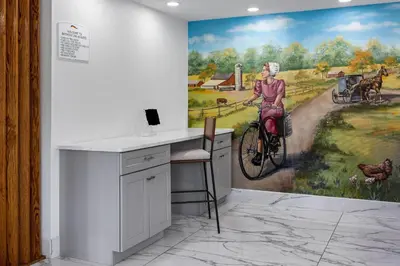 a room with a desk and a painting of a woman on a bike at Baymont by Wyndham Lancaster PA Dutch Country in Lancaster