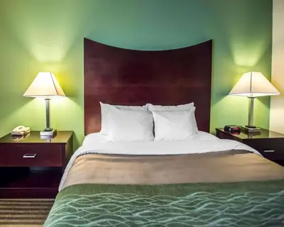 a bedroom with a large bed with two nightstands and two lamps at Quality Inn Mill Hall - Lamar in Clintondale