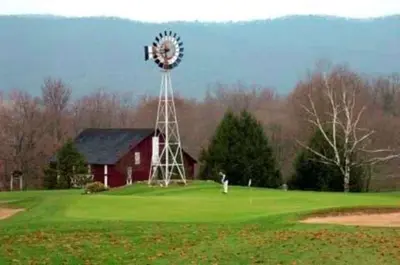 a windmill in front of a red barn with a green yard at Quality Inn Mill Hall - Lamar in Clintondale
