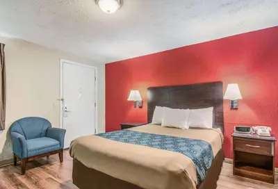a hotel room with a bed and a chair at Econo Lodge Mechanicsburg - Harrisburg West in Mechanicsburg