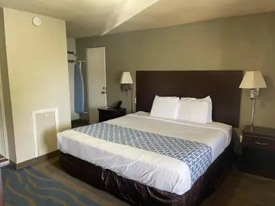 a hotel room with a large bed with white sheets at Econo Lodge Mechanicsburg - Harrisburg West in Mechanicsburg