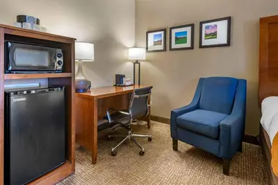 a hotel room with a desk and a tv and a chair at Comfort Suites Bethlehem Near Lehigh University and LVI Airport in Bethlehem
