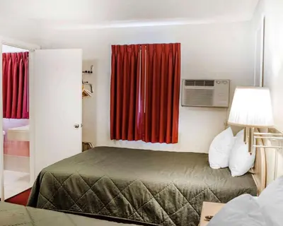 a hotel room with a bed and red curtains at Rodeway Inn Dillsburg in Dillsburg