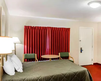 a bedroom with a bed and a red curtain at Rodeway Inn Dillsburg in Dillsburg