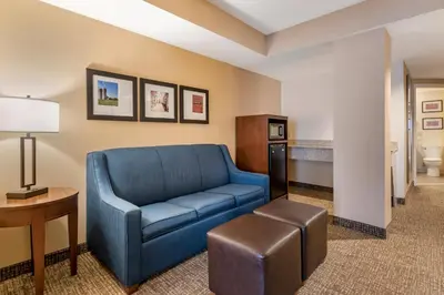 a living room with a blue couch and a table at Comfort Suites Downtown Carlisle in Carlisle