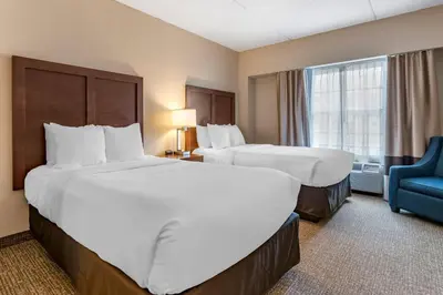 a hotel room with two beds and a blue chair at Comfort Suites Downtown Carlisle in Carlisle